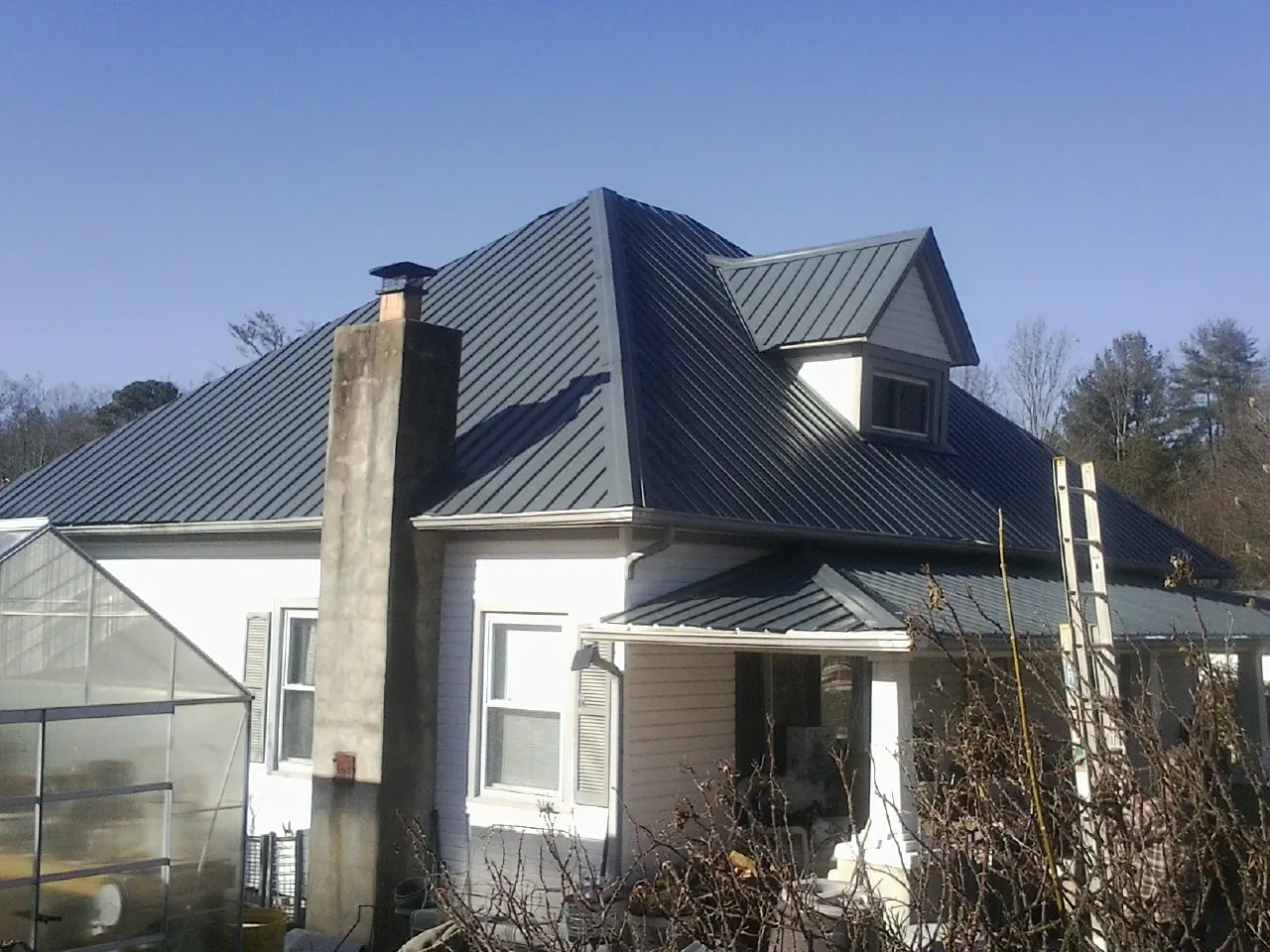 Dark blue standing seam metal roof on a white farmhouse with dormer — Slate & Tile Roof Repair by Roofing Brothers in Bowerston