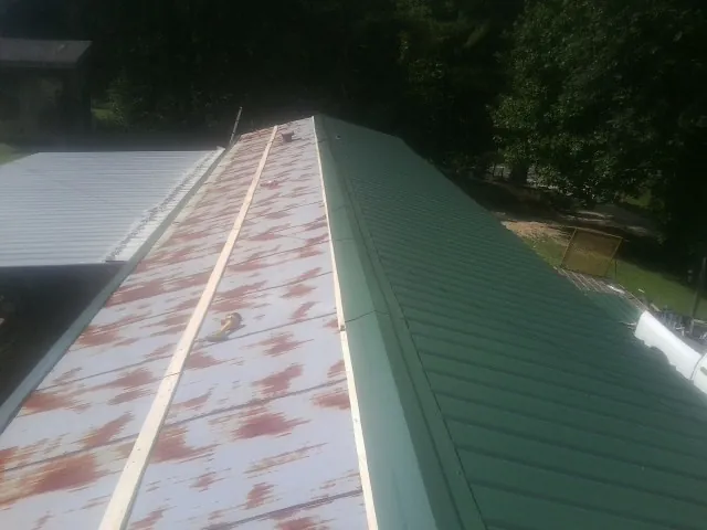 Old rusted panels beside newly installed green metal roofing — Wind Damage Roof Repair by Roofing Brothers in Bowerston