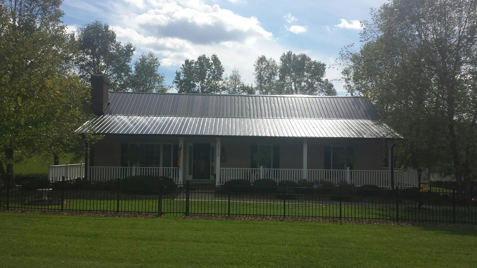 Gray metal roof on a brick ranch with a full width front porch — Gutter Guard Installation work by our crew in Bowerston